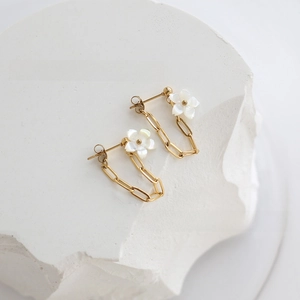 Detail of flower earrings with mother-of-pearl petals and gold chain on stone
