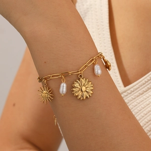 Bracelet chaîne dorée avec pendentifs soleil, tournesol et perle baroque sur poignet