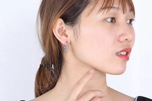 Close-up of polished silver beaded hoop earrings worn on a model for a chic look