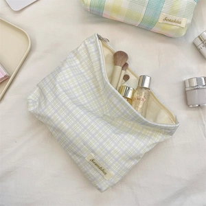 Detail of grid pattern cosmetic bag showing storage for makeup brushes and skincare
