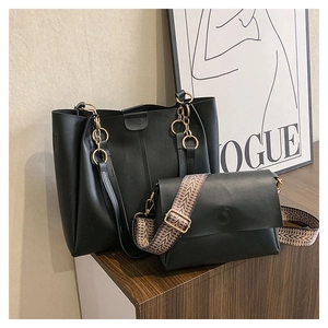 Detailed set of a black faux leather tote with gold chain and a small crossbody bag