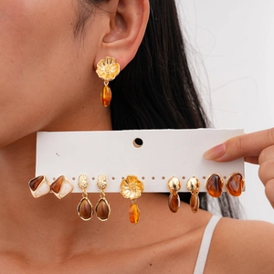 Macro detail of vintage gold flower earrings with amber resin and geometric pendants