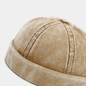 Detailed close-up of camel corduroy fabric texture and stitching on the retro brimless cap