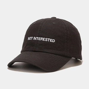 Close-up of NOT INTERESTED embroidery on black cotton twill baseball cap with vents