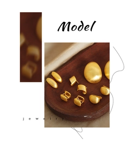 Detailed macro view of matte gold geometric earrings arranged on a wooden tray