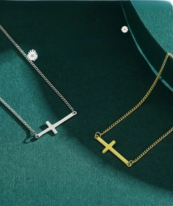 Macro shot of silver and gold horizontal cross pendants on deep green textured fabric