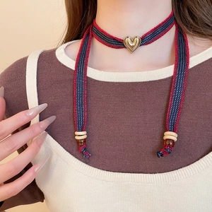 Close-up of woven striped choker with a gold heart pendant and beaded wood accents