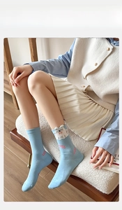 Detail of light blue crew sock featuring a 3D white cat embroidery and pink bow detail