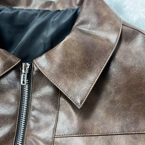 Dettaglio ravvicinato del colletto della giacca in pelle marrone e zip in metallo argento
