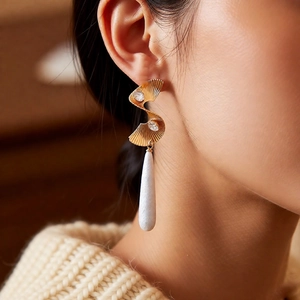 Detail of twisted gold earrings with dual zircon stones and a white waterdrop pendant