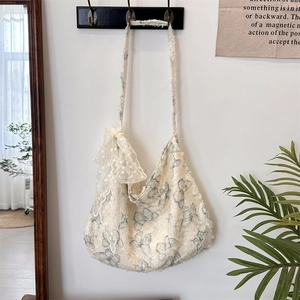 Detail of lace frill edges and butterfly print on a cream canvas shoulder bag