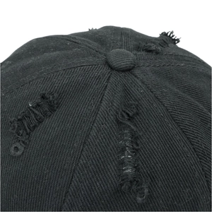 Macro detail of black cotton baseball cap showing distressed torn texture and vintage wear