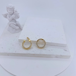 Close-up of gold-plated geometric earring connectors with pavé crystals on a stone tray