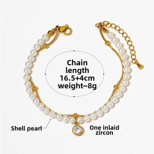 Detail of gold double-layer bracelet with white shell pearls and a round zircon pendant