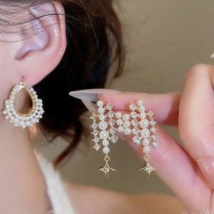 Close-up of pearl earrings featuring gold star pendants and sparkling zircon details