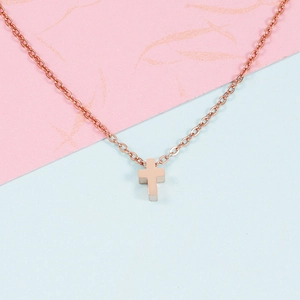 Close-up of rose gold cross pendant on thin O-chain over pink and blue background