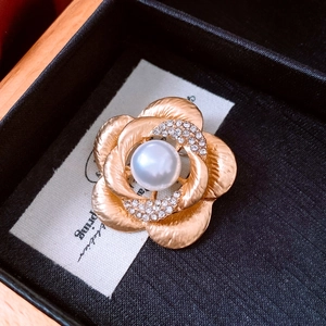 Detail of flower brooch with brushed gold petals, large center pearl and sparkling crystals