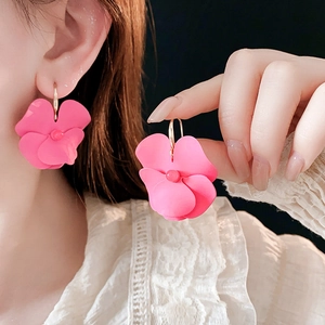 Close-up of model wearing vibrant pink floral earrings with layered petal design