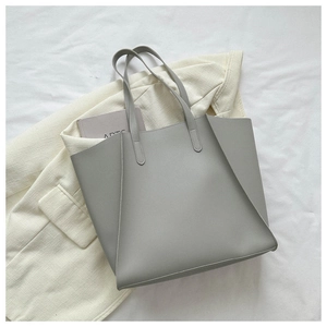 Flat lay of minimalist light grey large tote bag on a beige blazer with soft lighting