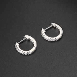 Detail of silver stainless steel huggie earrings with zircon inlays on gray texture