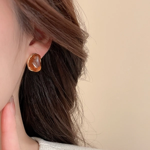 Vue détaillée des boucles d'oreilles goutte en résine ambre et bordure dorée