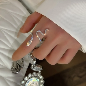Close-up of silver snake ring with pavé zircons worn on finger, adjustable open design