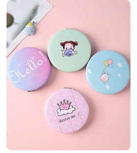 Flat lay of four colorful round portable makeup mirrors with cute cartoon patterns