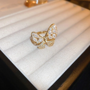 Close-up of golden butterfly ring with pearls and crystals in a velvet jewelry box