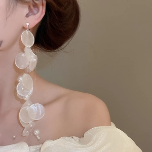 Detail of elegant cream-white pearl and iridescent shell tassel earrings for women