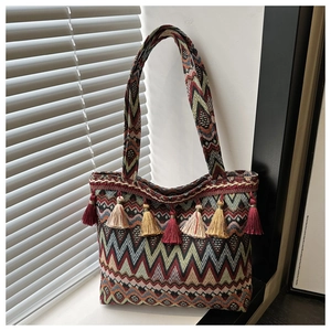 Detail of colorful geometric woven tote bag with bohemian tassels in natural sunlight