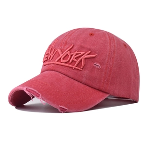 Detailed view of New York embroidery and distressed frayed edges on pink baseball cap