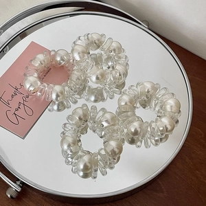 Gros plan de cinq élastiques à cheveux spirale transparents avec perles sur un miroir
