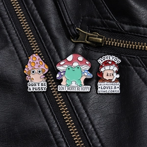 Detailed close-up of colorful enamel mushroom and frog pins on a black leather jacket