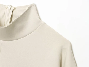 Detail of high neck beige outfit with textured twill fabric and hidden back zipper