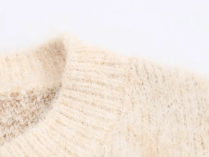 Close-up of cream knit sweater collar and shoulder showing soft jacquard texture