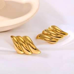 Polished 18k gold-plated angel wing earrings on elegant silk background fabric