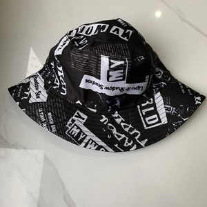 Detailed top view of black and white newspaper print cotton bucket hat on marble background