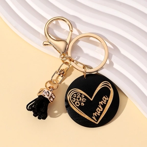 Detail of mama keychain with black round pendant, leopard heart print, and soft tassel charm