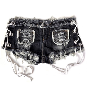 Dettaglio ravvicinato di shorts in denim strappati con lacci laterali e bordi sfilacciati