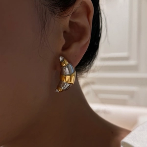 Close-up of stylish gold and silver two-tone croissant hoop earrings worn by a model
