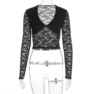 Close-up of intricate floral lace texture and ribbon bow on black V-neck crop top