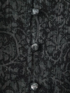 Nahaufnahme des Stoffknopfs am V-Ausschnitt-Kleid mit Blumenmuster und silbernen Lurexfäden