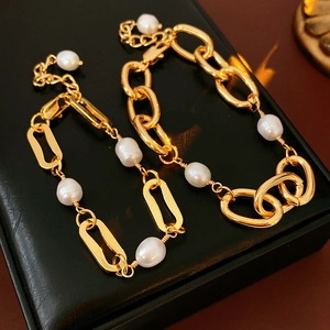 Detail of gold-plated chain bracelet with freshwater pearls on black leather background