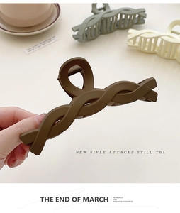 Close-up of a large matte-finish twisted claw clip for women's hair in deep brown