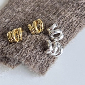 Detailed view of silver and gold spiral hoop earrings on a textured knit background