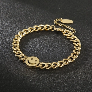 Macro detail of gold stainless steel twisted chain bracelet with a smiley face pendant