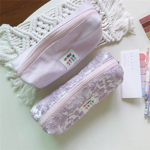 Detalle de estuches morado claro con texturas de pana y bordado de encaje fino
