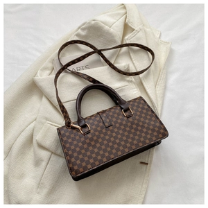Detail of brown geometric printed handbag with gold hooks on beige fabric background