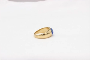 Detail view of a wide gold titanium ring featuring an oval blue lapis lazuli gemstone