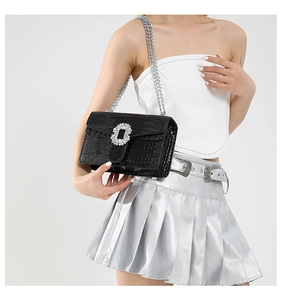 Detail of black crocodile texture bag with rhinestone buckle and silver chain
